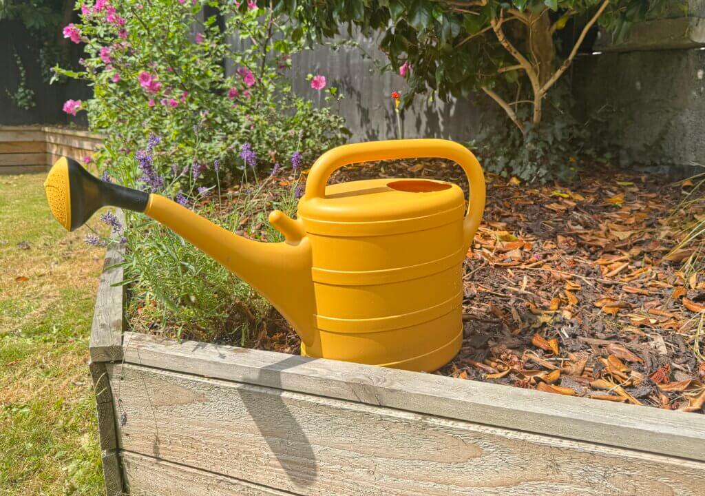 A yellow watering can in the garden